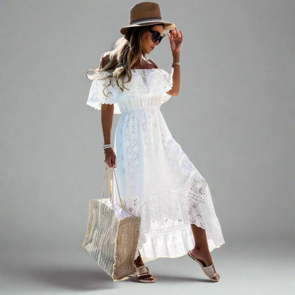 Woman wearing a white lace dress and straw hat on a gray background